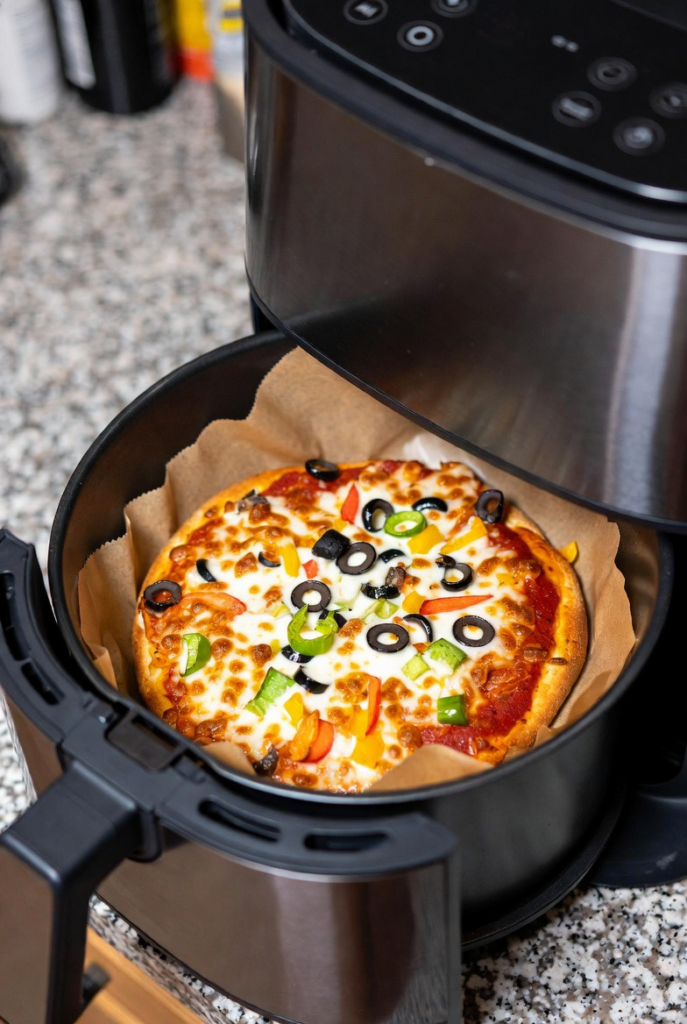 parchment paper inside an air fryer with pizza