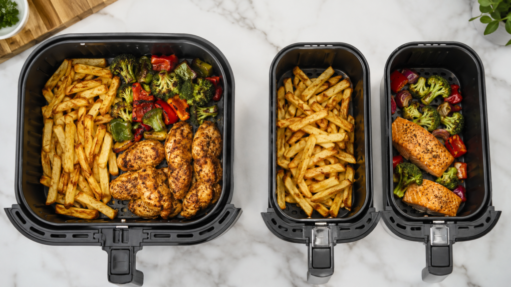 Air fryer food arranged in one large basket and two smaller baskets